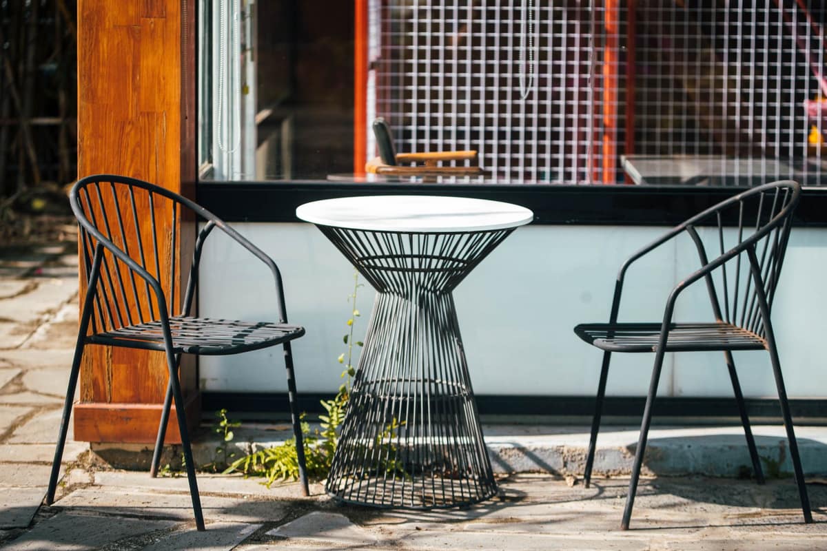Stylish outdoor café setup featuring modern metal chairs and a round table.