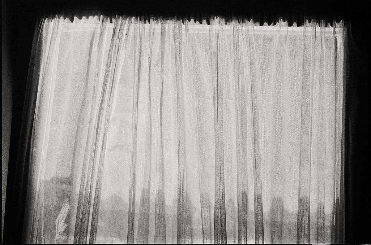 Black and white photo of sheer curtains with a sense of mystery and subtle lighting.